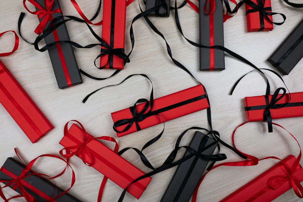 Stylishly wrapped red and black gift boxes arranged in a flat lay on a wooden surface.